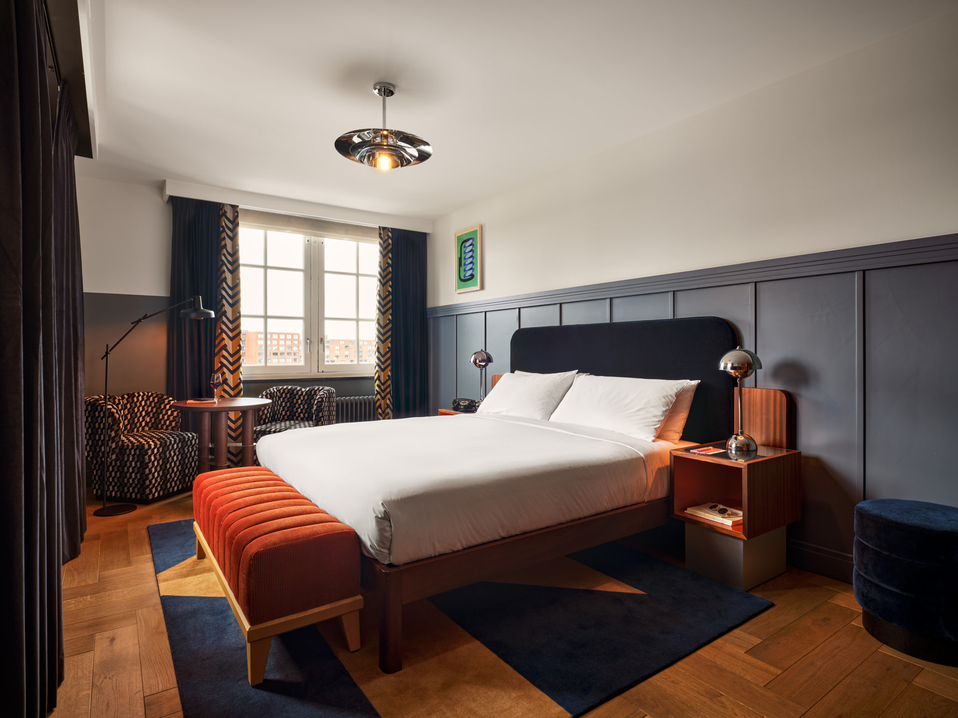 Wide shot of the Biggy room with hardwood floors, lots of space and wide window with big bed